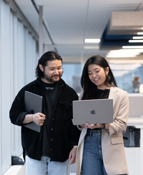 Two people are holding laptops in the office